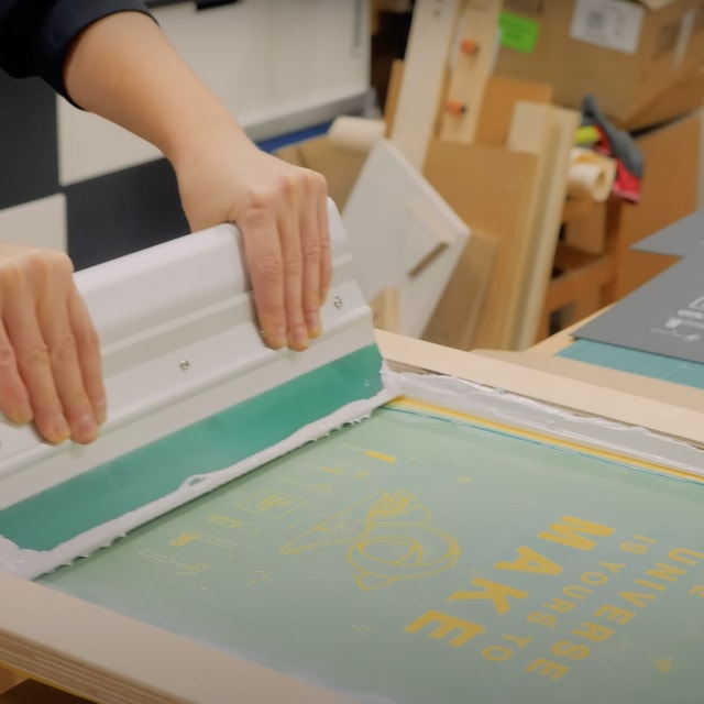 focus on  Cirstina's hands while printing white ink on black posters