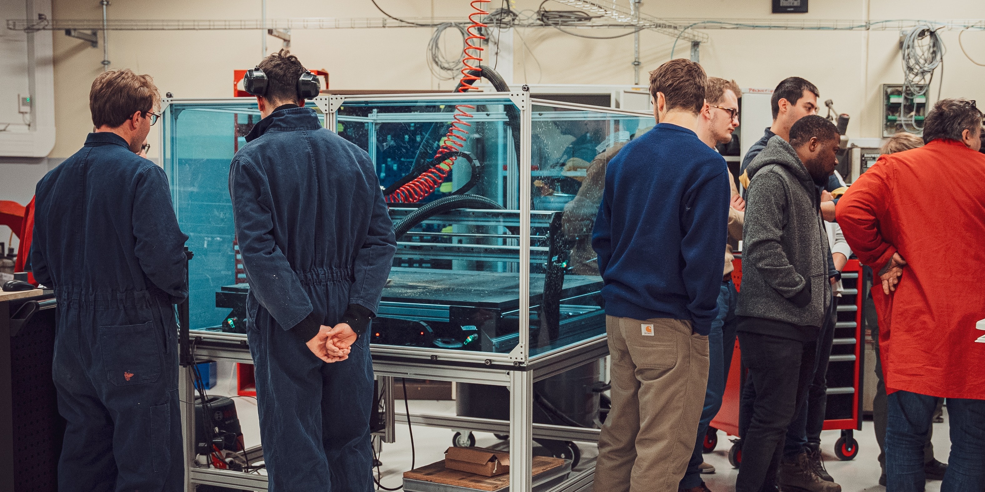 Few students are watching the working Mekanika Pro CNC milling through the plexiglass sheets of the ssafety enclosure