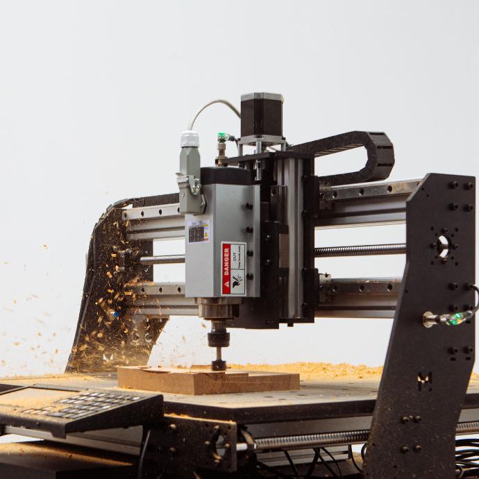Mekanika Pro CNC milling machine milling wood with a large end mill on white background