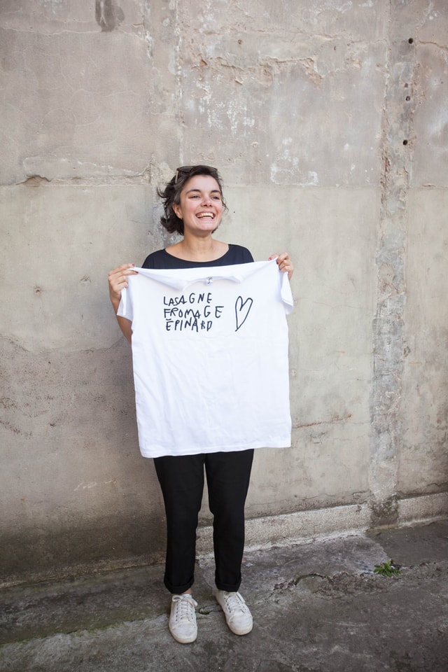 Mahé holding her t-shirt "Lasagne fromage épinard" made on a Mekanika screen printing press