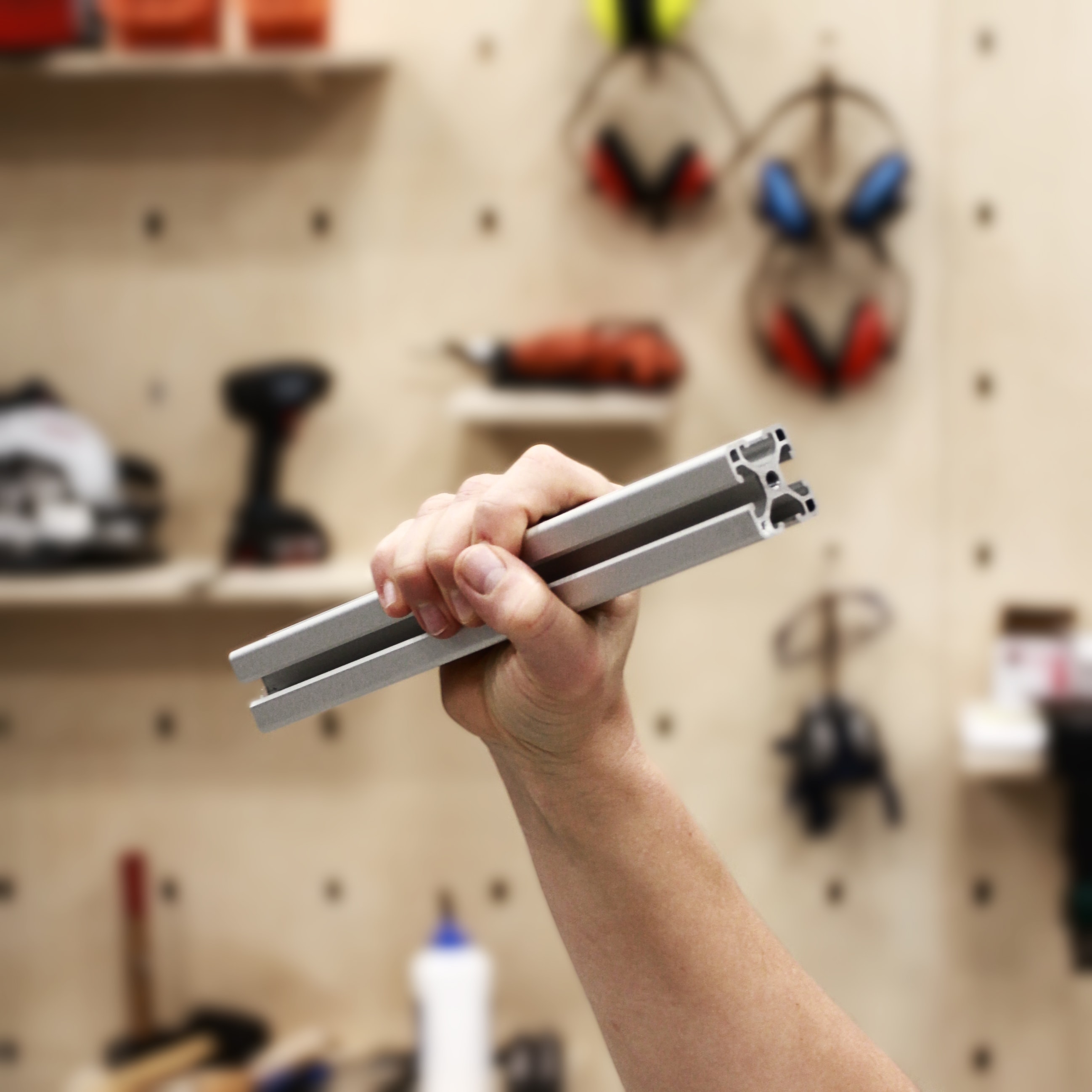 Clenched fist holding an aluminium profile in a revendicative way with tools in the background
