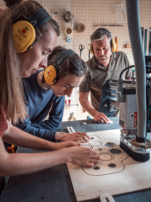 Timelab gent Members next to their Mekanika Pro and checking if their wooden prototype corresponds to what they want