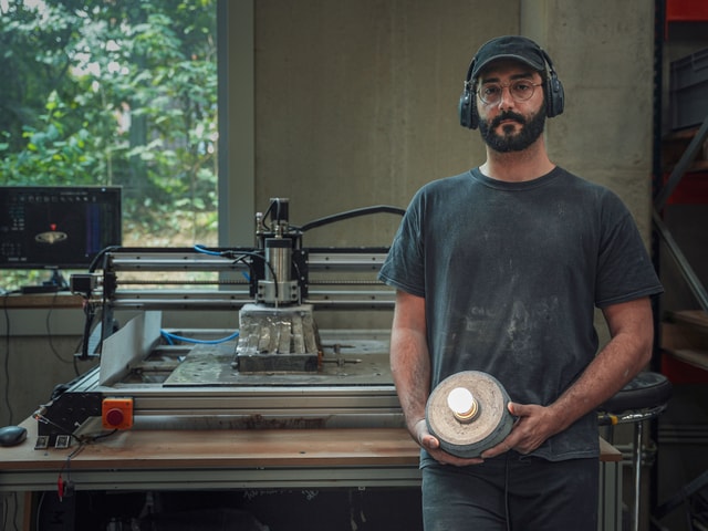 Hippolyte from Duplex Studio standing next to his Mekanika Pro with his lamp product in hand