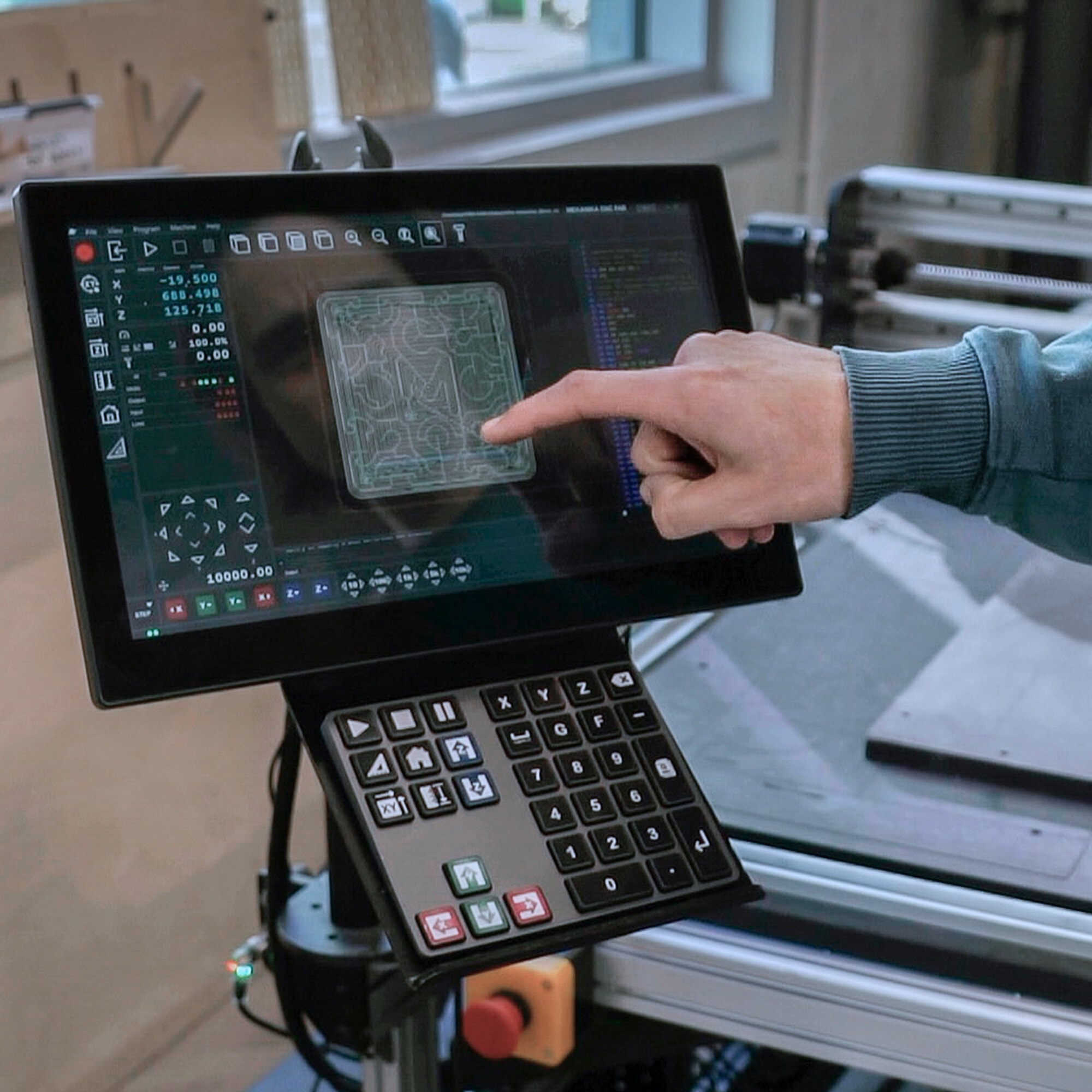 Someone pointing the machine interface showing the design and G-code