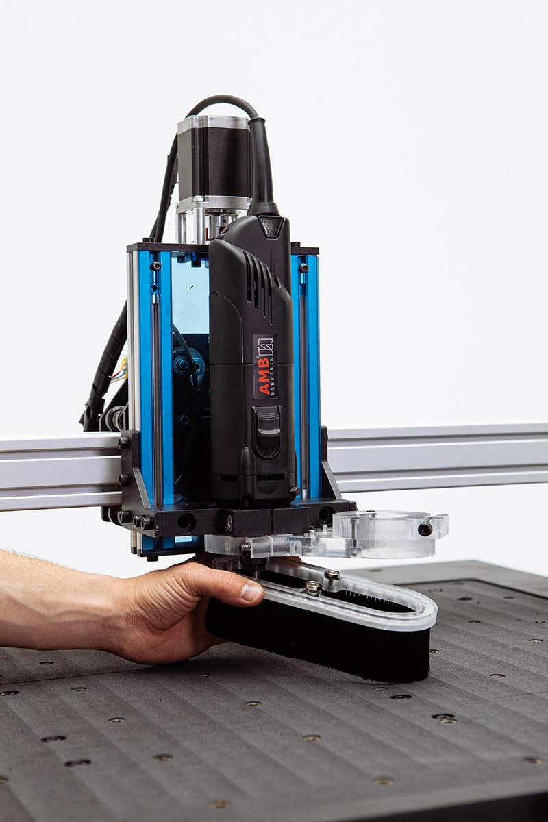 Mekanika Evo CNC milling machine close up of a hand placing the dust shoe brush part on the AMB spindle