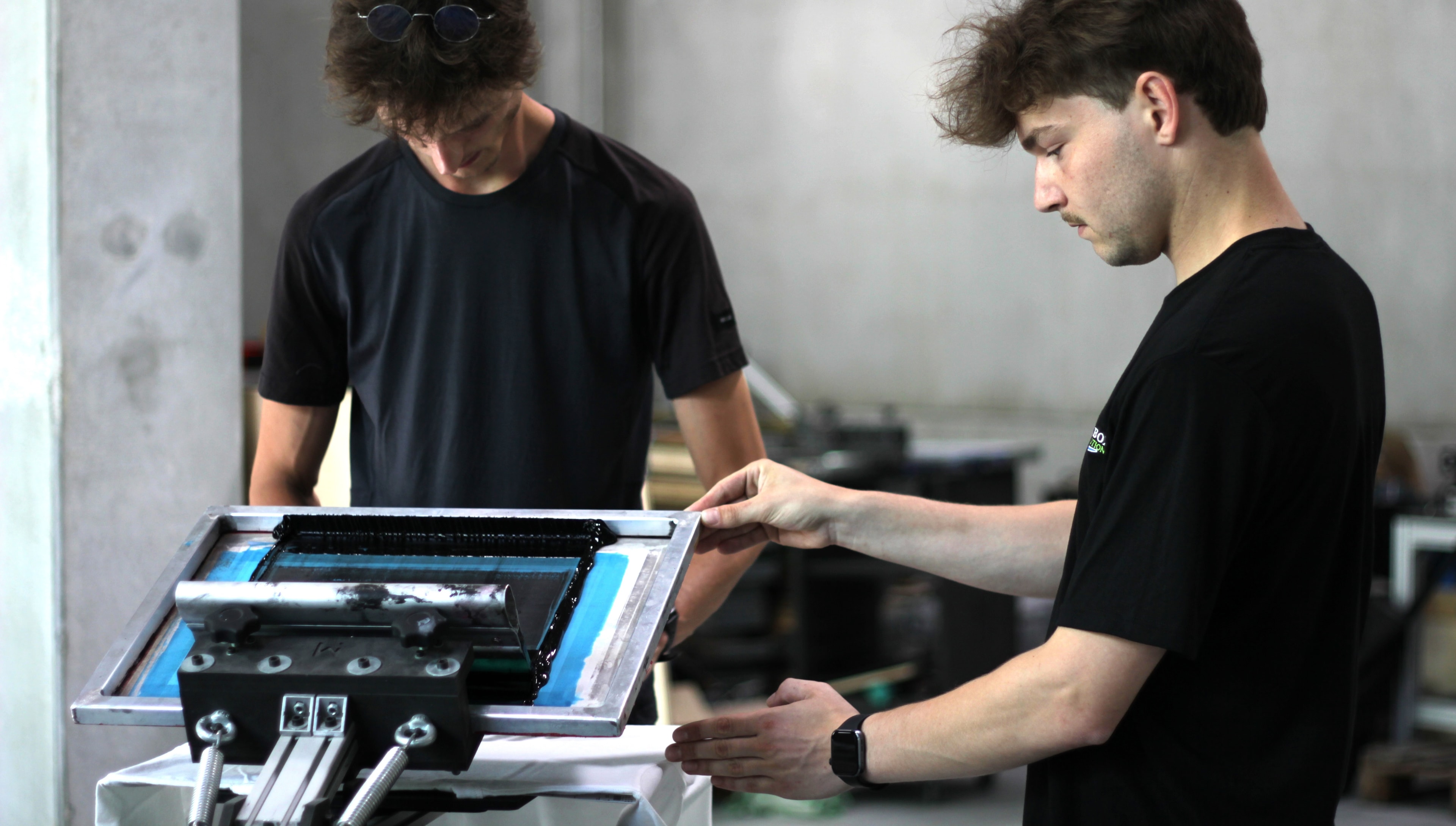 Two people printing t-shirt with the Mekanika screen printing press