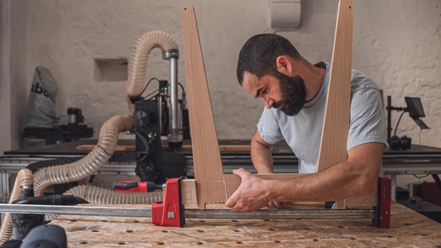 Haddock in his workshop asembling a stool while the Mekanika Fab is working in the background