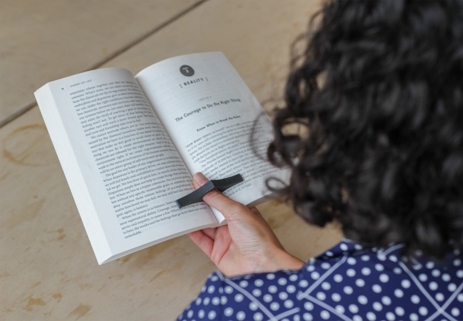 Close up on the hand of a person holding a book with a page holder on the thumb