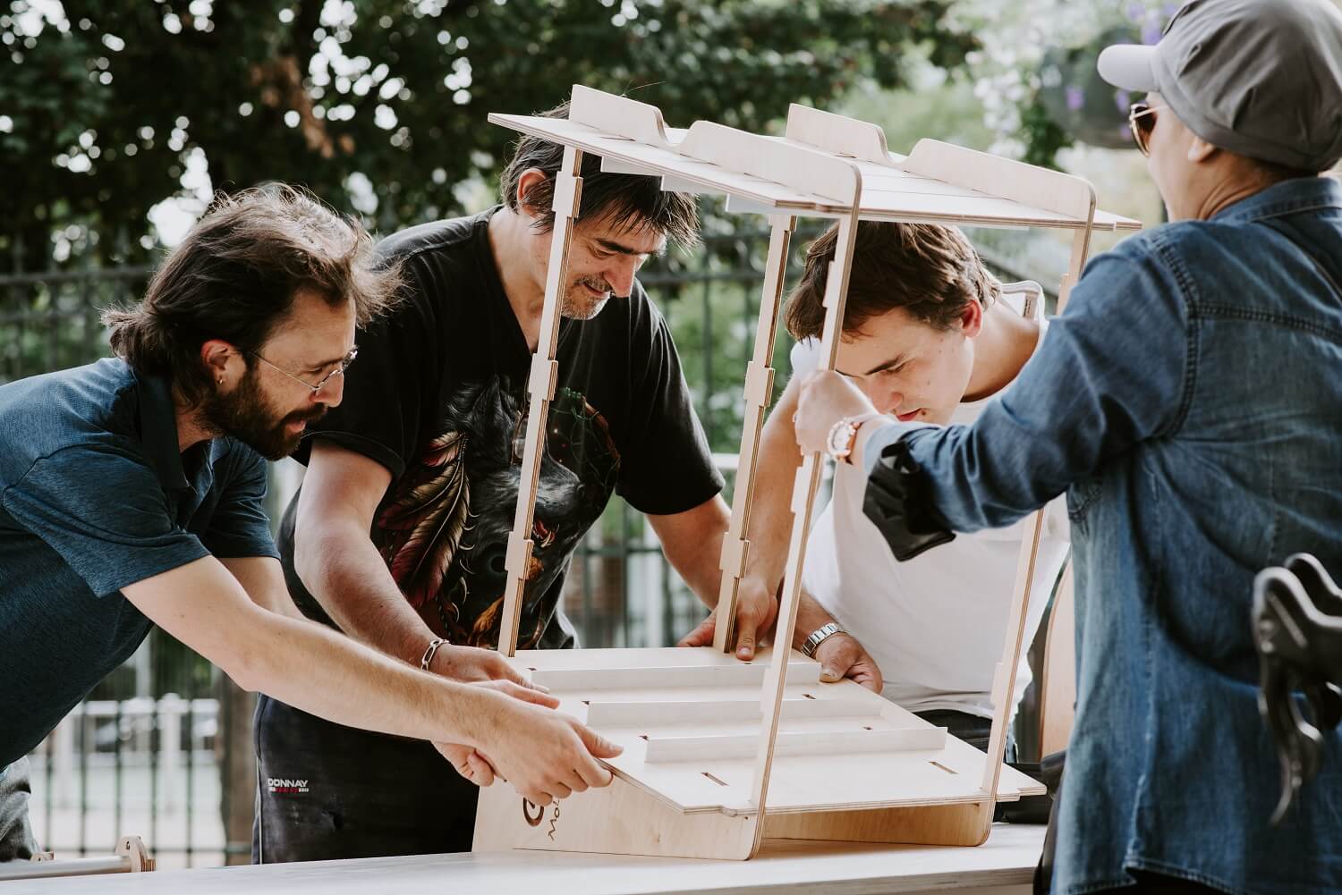 Four men assembling cargo bike furniture made on a CNC